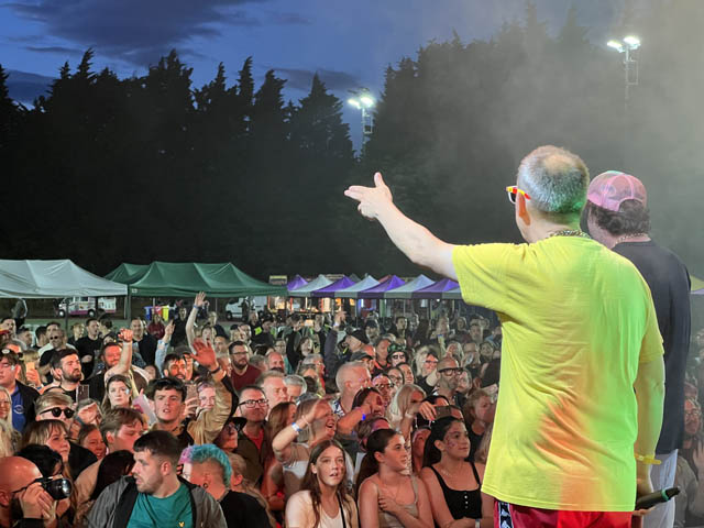 a rap band perform to a large outdoor crowd