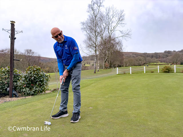 a man putts a ball on a golf course