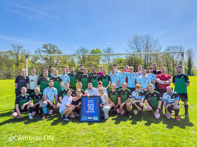 two football teams and some supports have a photo on the football pitch