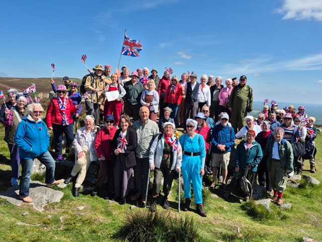 a large group of walkers stood outside some waving union jack flags