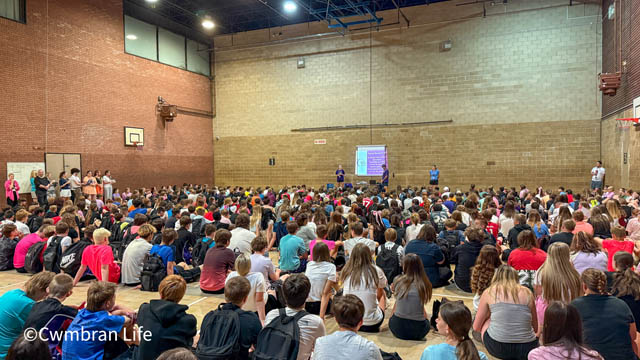 a few hundred pupils sat on the floor watch a presentation about cancer
