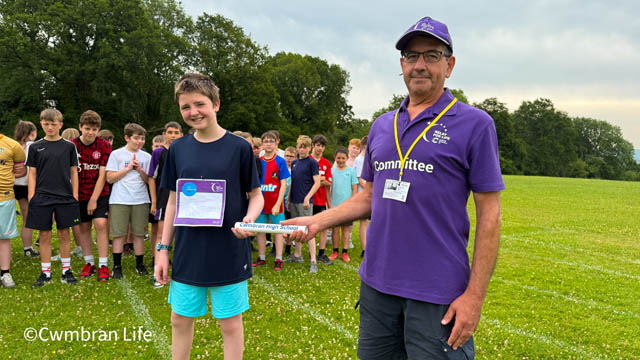 a teenage boy and a man hold a baton on a sports field