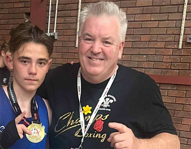 a boxer and his coach- the boxer is holding a medal