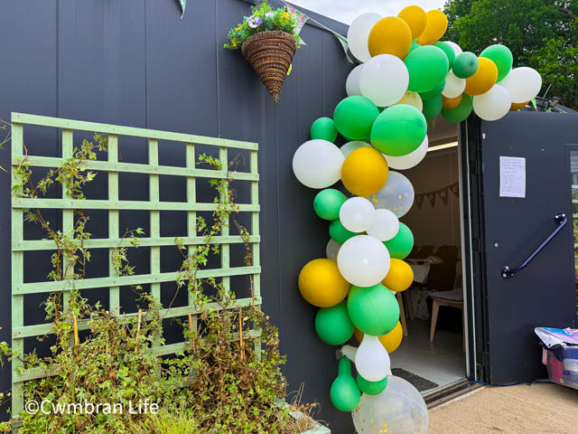 green, white and gold balloons cover the entrance to a building