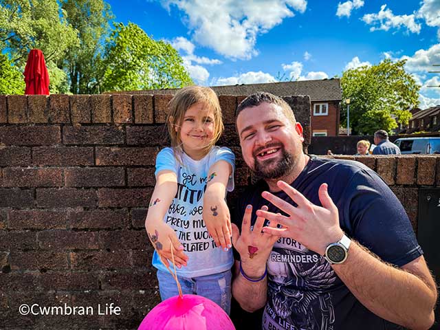 a man and his daughter kneeling down showing their painted nails