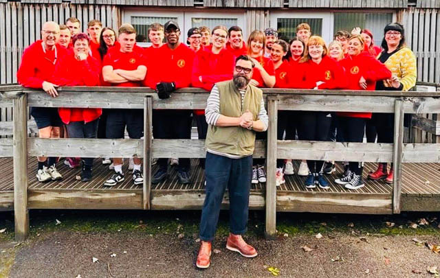 a man in front of a large group of people most in red jumpers