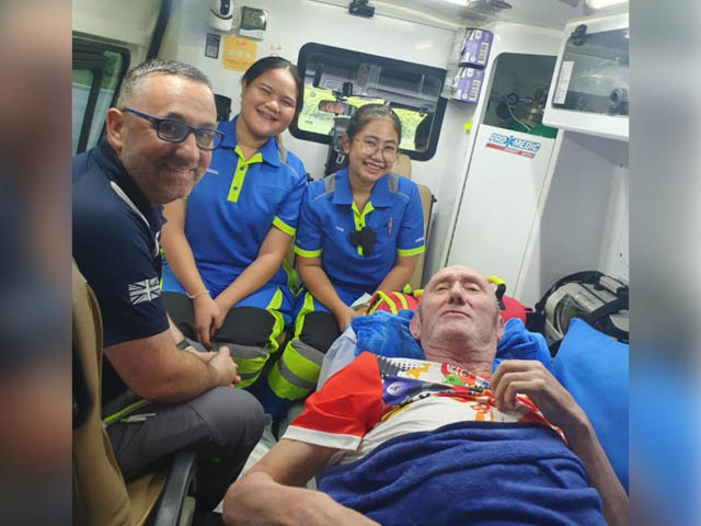 a man lying down in am ambulance with three medical staff next to him