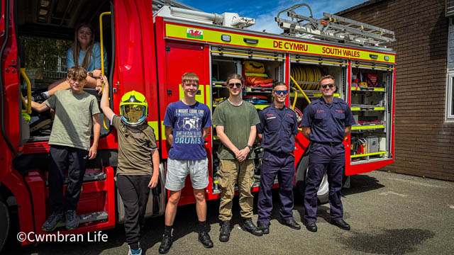 five school pupils and two firefighters by a fire engine