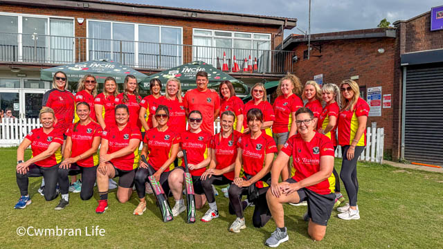 a group of female cricketers outside their club with their male coach