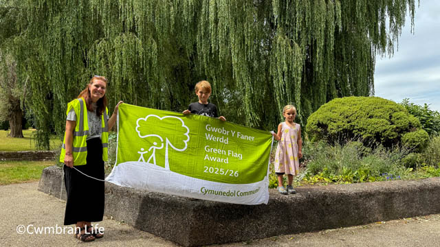 Bethan Oliver and her two children holding the Green Flag Award in Oakfield Flower Gardens today.