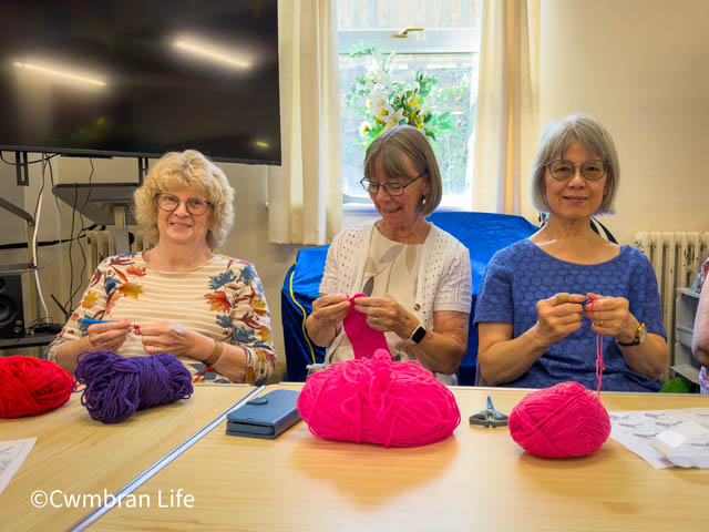 three women crocheting at a table