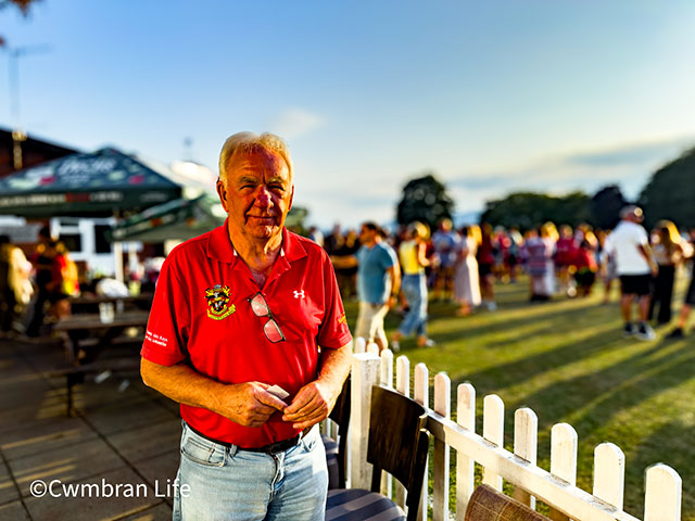 a man in red shirt next to a cricket field