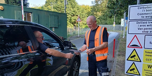 a car driver shows ID to man in a high viz jacket