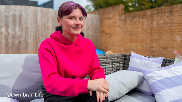 a teenage girl sat on a sofa in a back garden