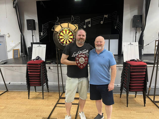 two men stood in front of a darts board