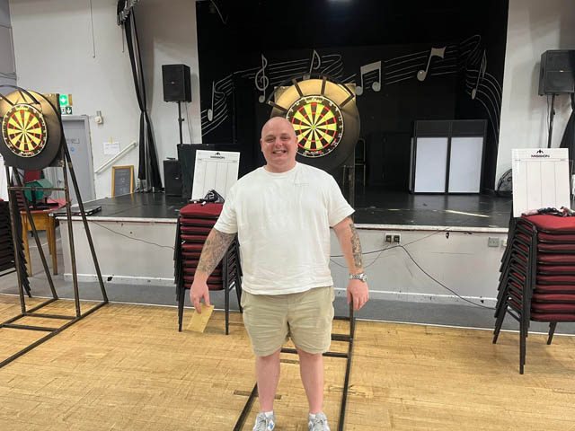 a man stood in front of a darts board