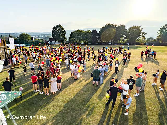 a crowd of people on a grass pitch on a sunny evening