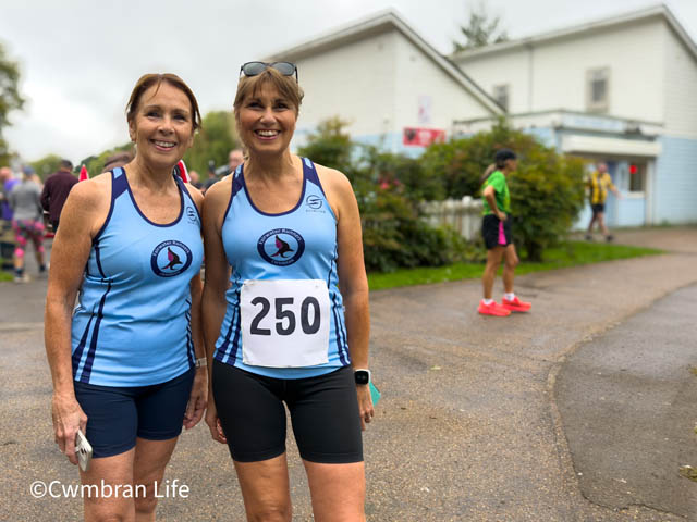 two women in blue running vest, one with the number 250 on it, before a running event