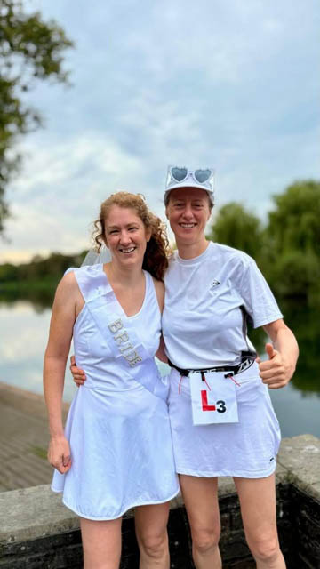 two women in white stood in front of a lake