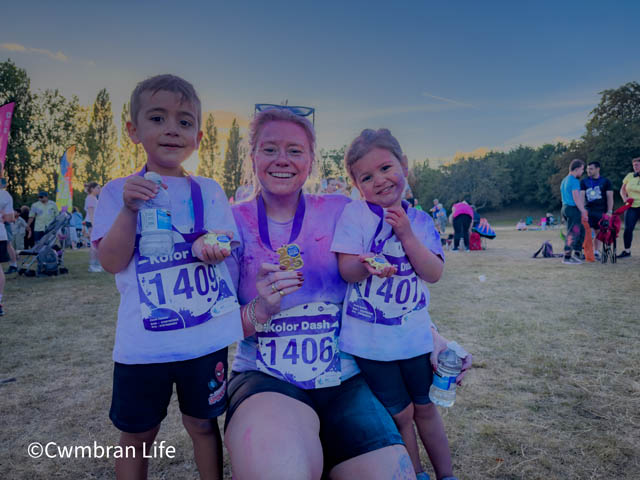 a woman with two young children holding up medals after a 5km run