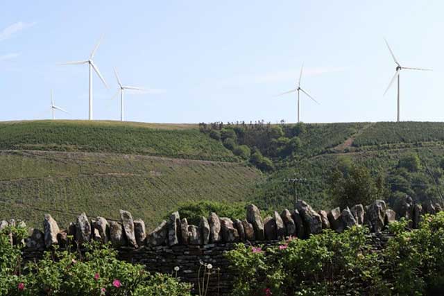 grassland on a mountain with some wind farms in the distance