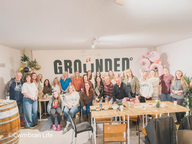 group of men and women by a pink balloon arch in a cafe