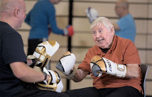 a man holds boxing pads for a man in boxing gloves to punch