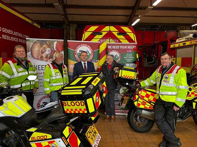 several men, some in high viz jackets standing by motorbikes