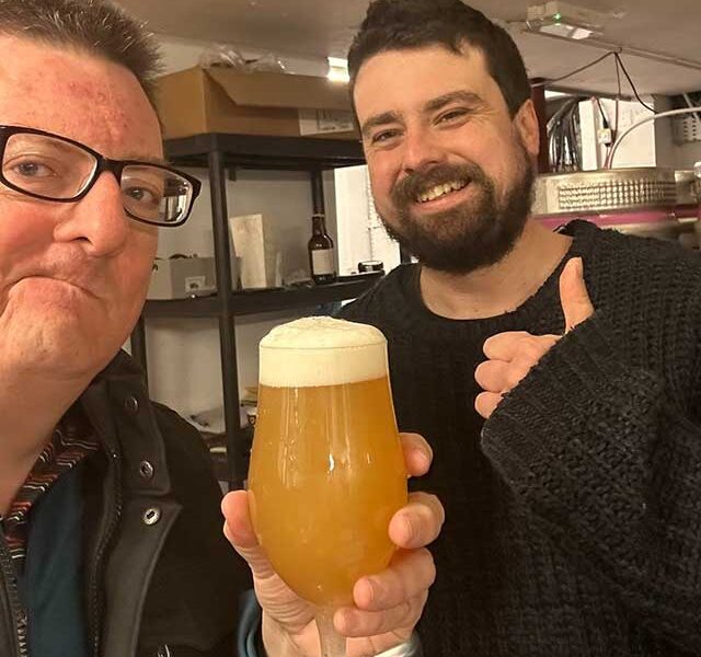 two men, one holding a beer