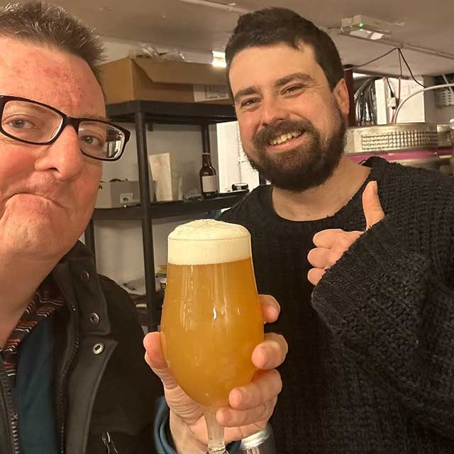 two men, one holding a beer