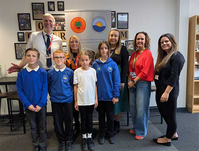 adults and staff in a school corridor smile for a photo