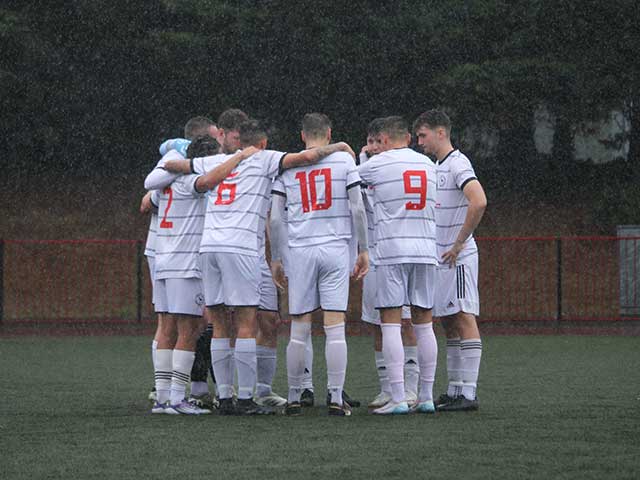 a men's football team in a huddle in the rain