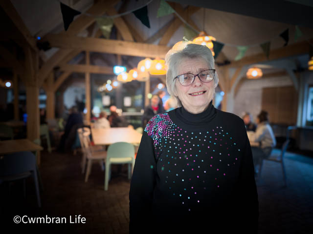 a women smiles at camera stood up in a cafe