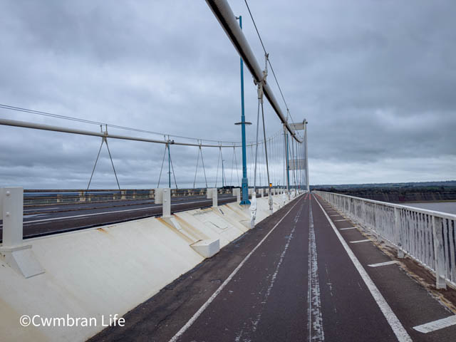 a footpath on a bridge over water , next to a motorway