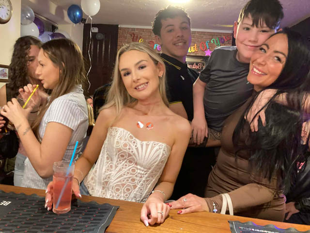 a gropu of women and two boys at the bar of a pub