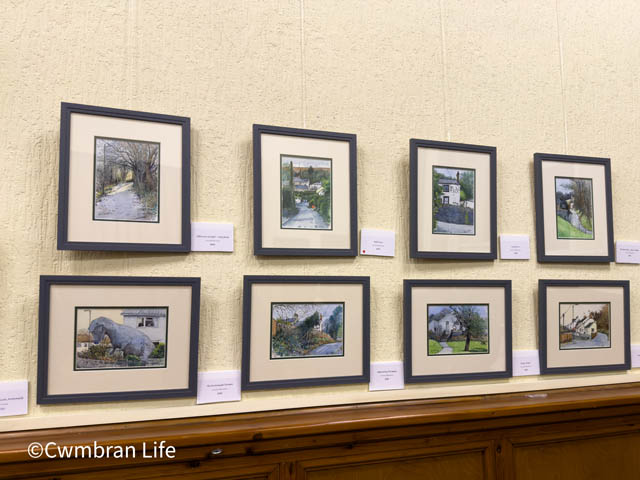 eight paintings on display on a wall