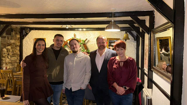 two women and three men stood in a row in a pub