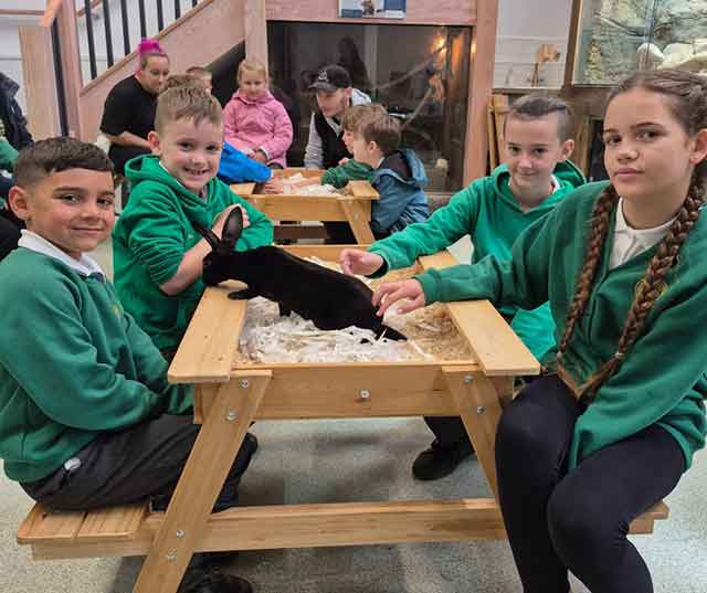 a group of children at a table with a rabbit