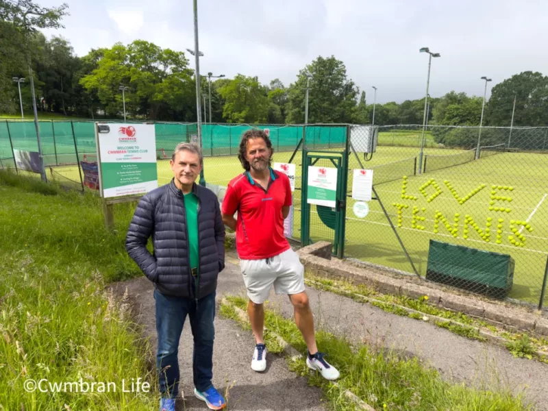 two men stood by a tennis court