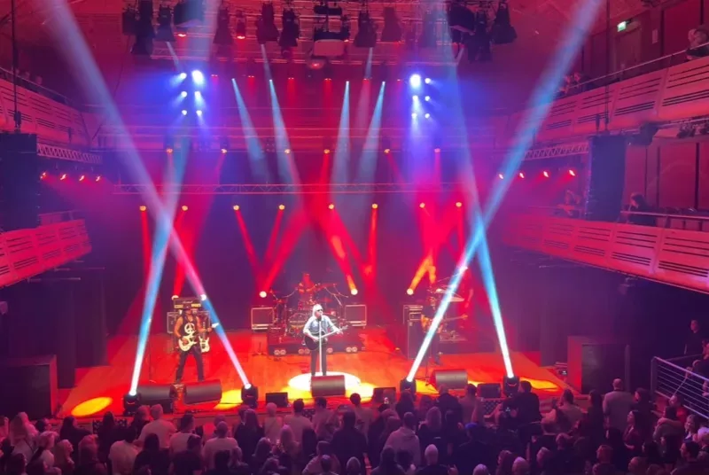 a band on stage playing to crowd with bright lazer lights across the stage
