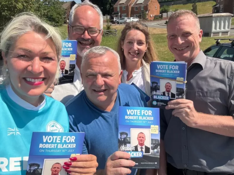 a group of people holding Reform UK flyers