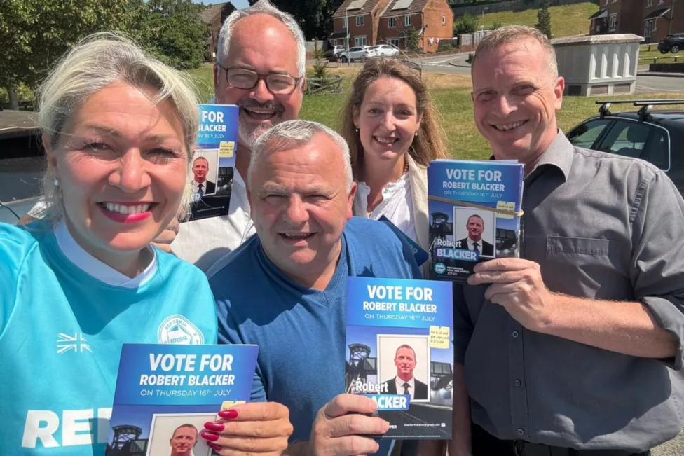 a group of people holding Reform UK flyers