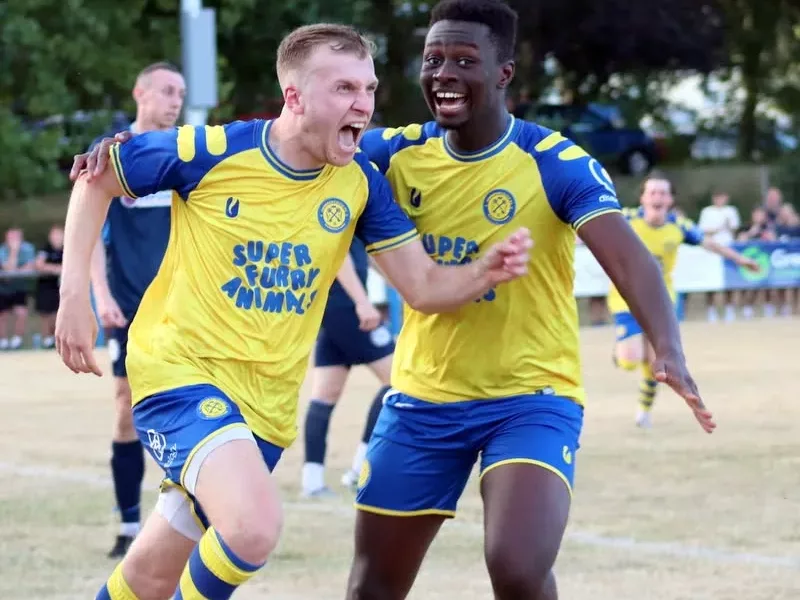 two footballers run and celebrate a goal