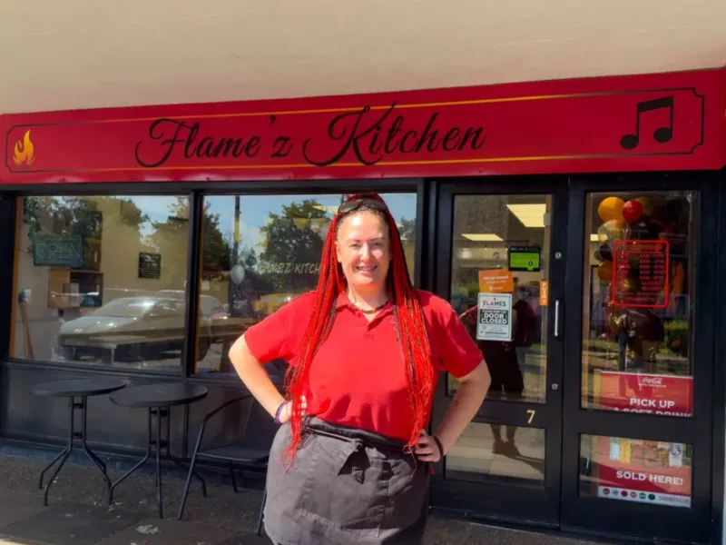a woman outside a shop called Flame'z Kitchen