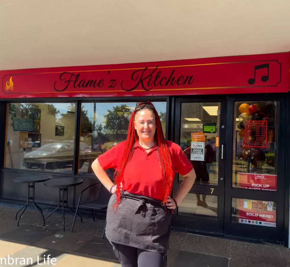 a woman outside a shop called Flame'z Kitchen