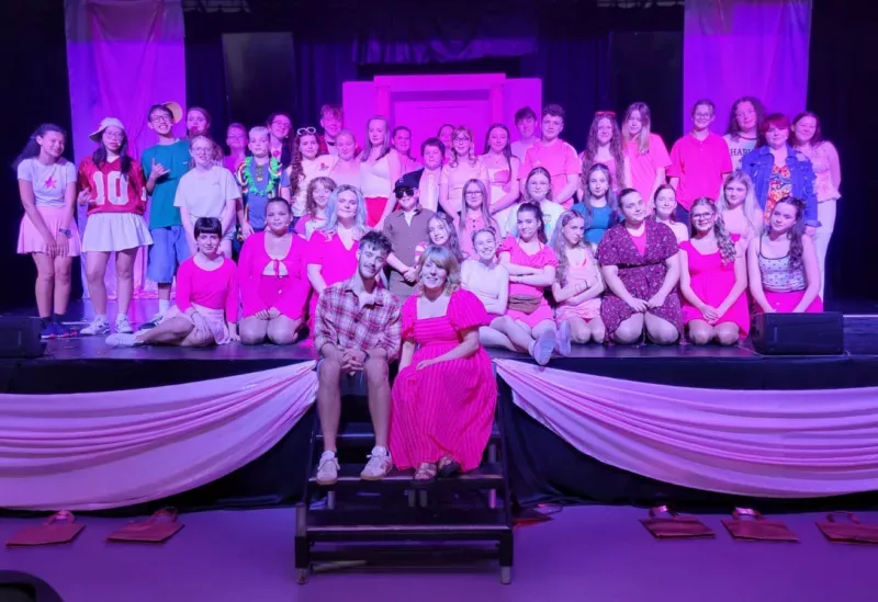 a large group of young people on a stage with two teacher on the steps