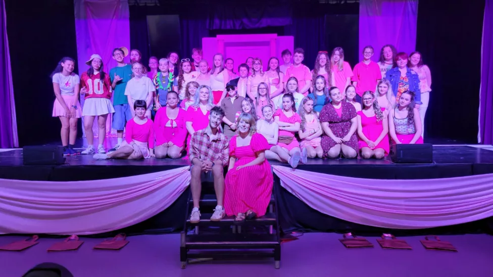 a large group of young people on a stage with two teacher on the steps