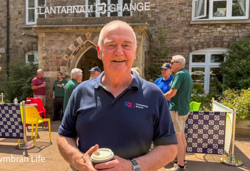 a man stood outside a building with aLlantarnam Grange sign on it