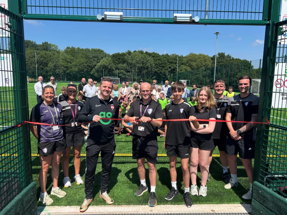 a group of people cut a ribbon on a sports pitch