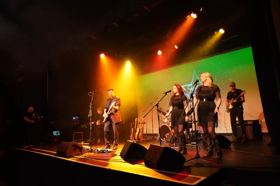 A singer/ guitarist on stage performing with backing singers